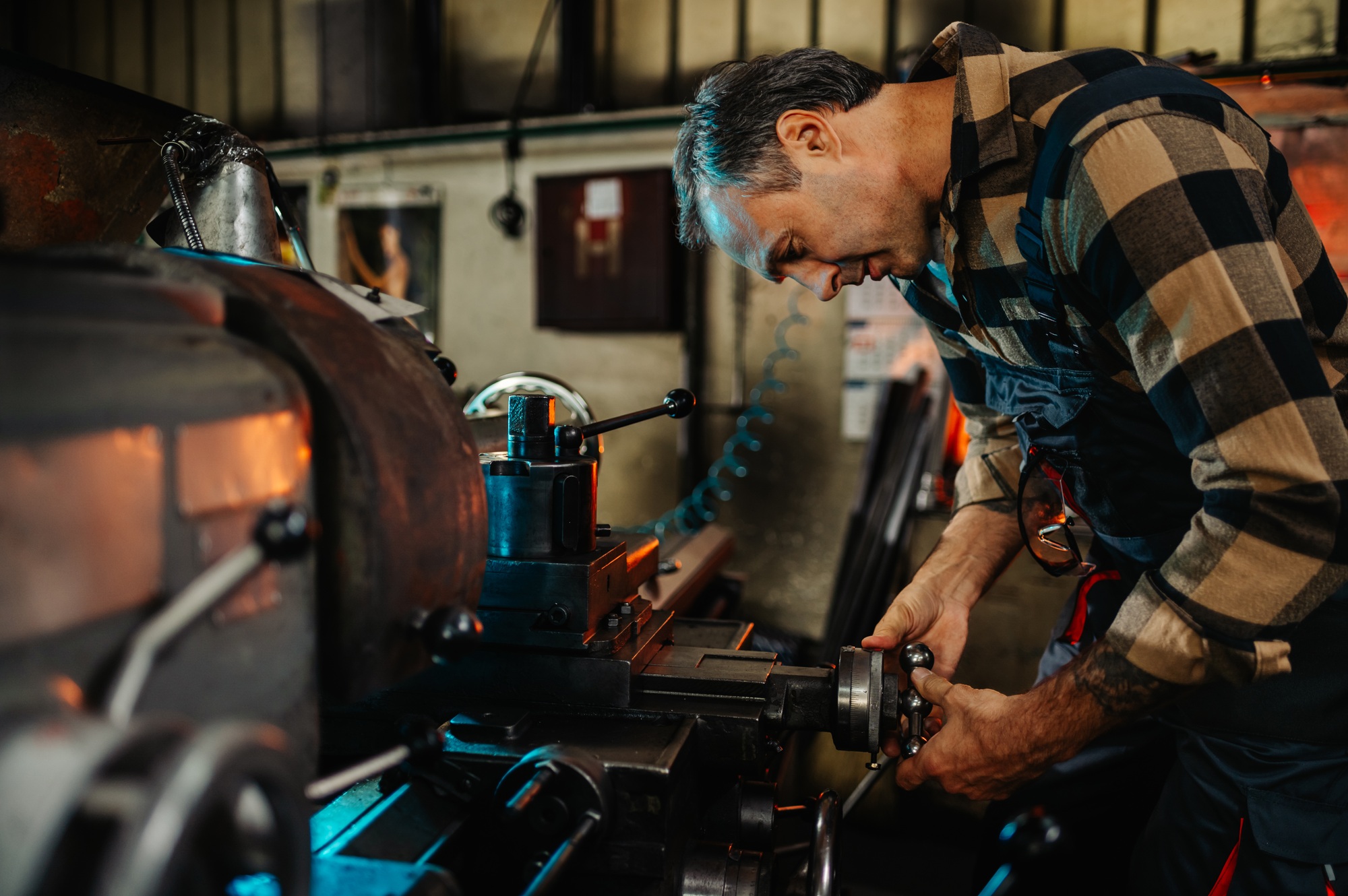 An engineer examining a knob on a factory machine, repairing, fixing.