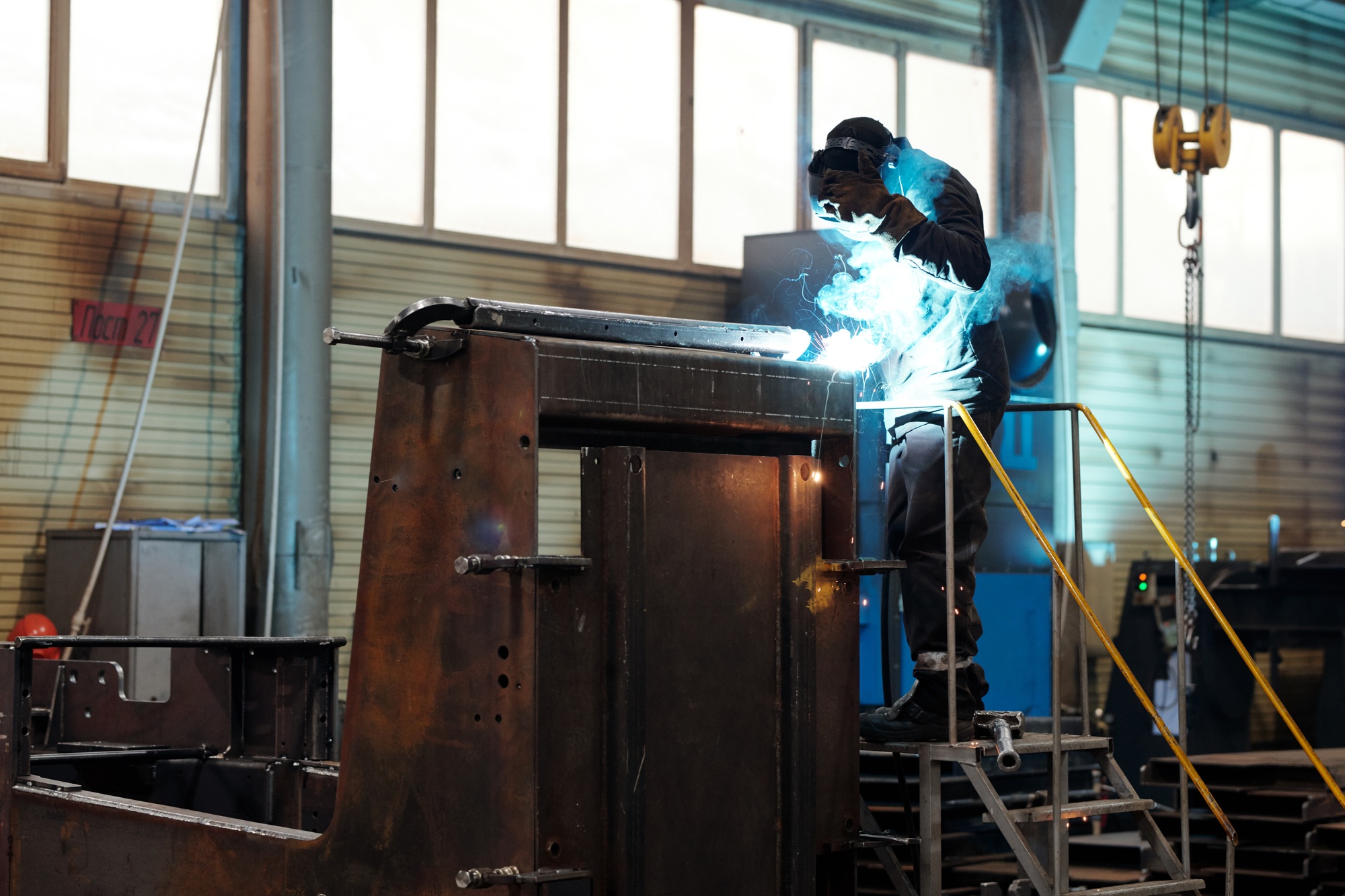 Contemporary worker or welder in protective mask and uniform repairing machine